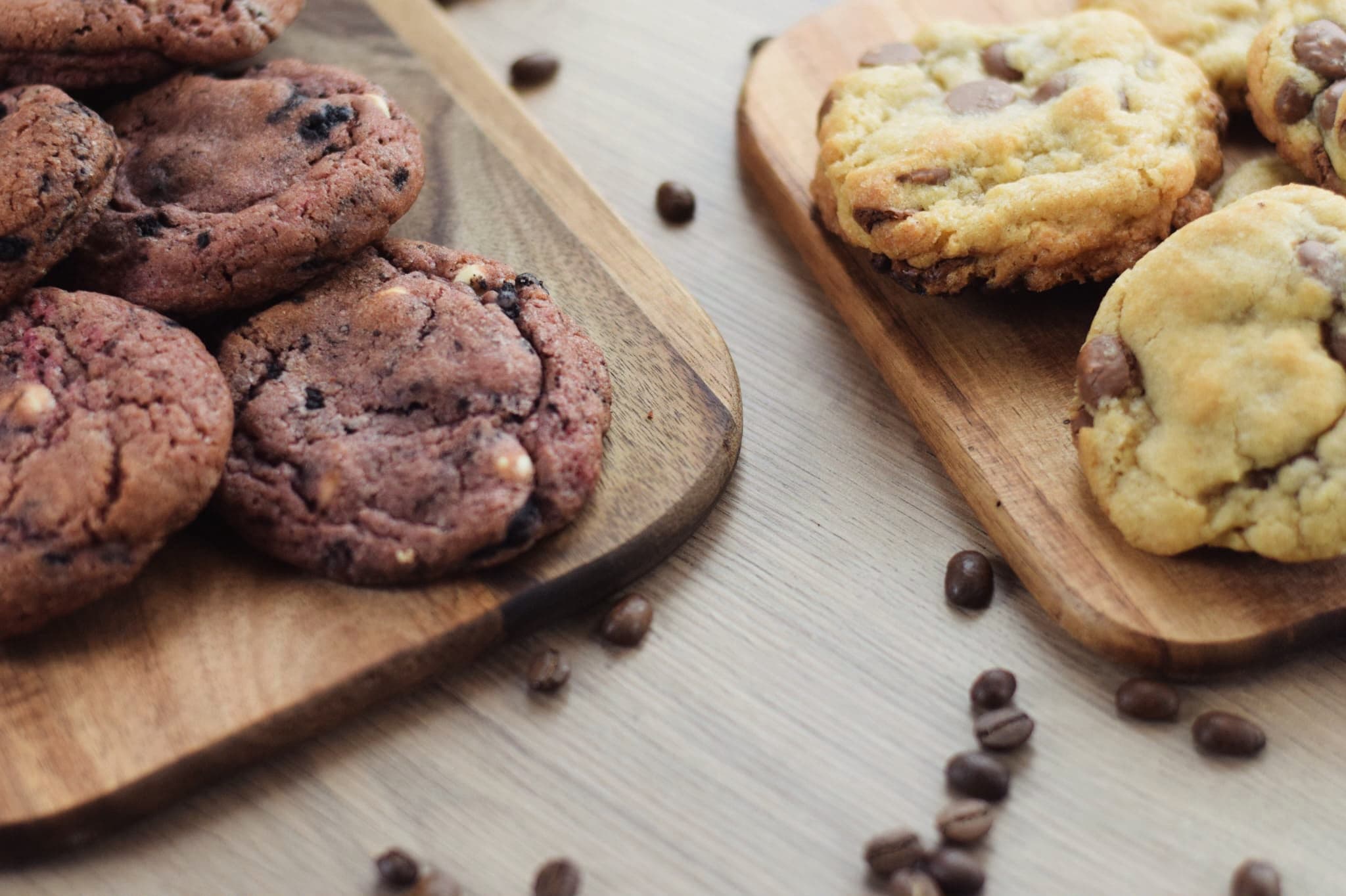 Twee houten plankjes met red velvet cookies en cookies met chocolade, met koffiebonen ertussen